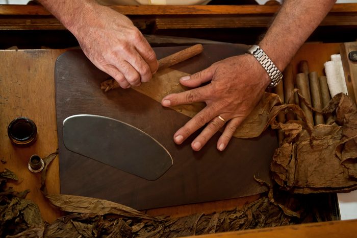 Hands hand-rolling cigars at the factory